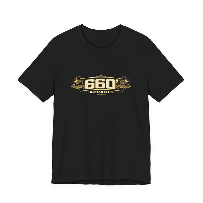 Front of black Bella+Canvas 3001 with wide cream-and-gold 660′ Apparel logo, shop lamps and engraved ornament